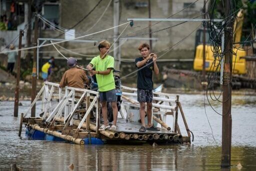 Residents use a boat to cross a public road that has been submerged for years by rising river levels following trash avalanches at the Cipayung landfill, Depok, West Java