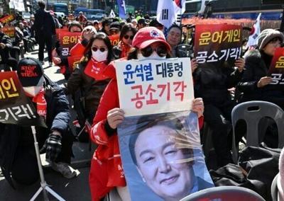 A supporter holds a portrait of Yoon Suk Yeol during the ex-president's earlier insurrection trial, which saw him jailed for life over his failed bid to impose martial law