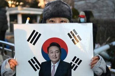A supporter of South Korea's impeached former president Yoon Suk Yeol holds a placard showing a picture of Yoon in front of the Seoul Central District Court in Seoul on January 13, 2026