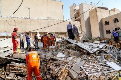 In this picture obtained from Iran's ISNA news agency, rescuers search through the rubble of a collapsed building at the site of a strike in Tehran