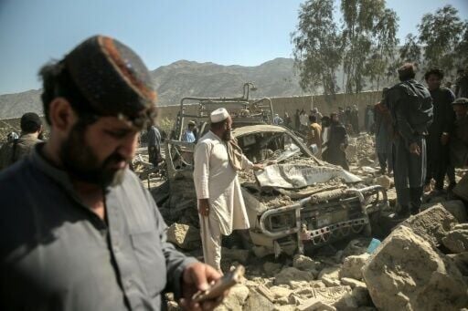 Afghan men gather near a damaged car after an overnight Pakistani airstrike hit a residential area at the Girdi Kas village in Bihsud district, Nangarhar province, on February 22, 2026