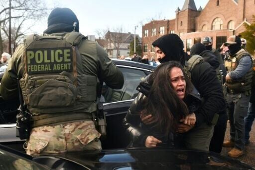 Masked officers drag a woman from her car as US immigration agents conduct checks in Minneapolis, Minnesota