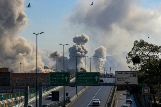 Motorists drive along an expressway as plumes of smoke rise after a strike in Tehran on March 5, 2026