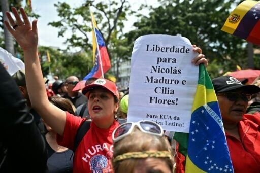 A woman holds a sign reading "Freedom for Nicolas Maduro and Cilia Flores!" and a Brazilian national flag during a demo of supporters of the ousted Venezuelan president in Caracas