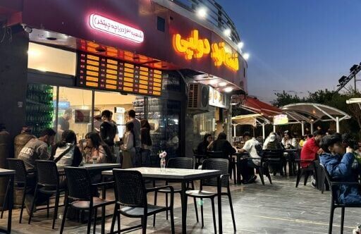 Iranians gather at an eatery in northwestern Tehran. Despite an outward appearance of normality, many are under severe financial strain