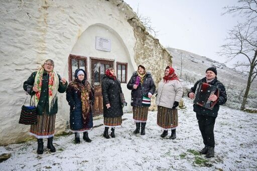 Local women in traditional dress sing carols outside a 'basca' hobbit house in Rogojeni, Moldova