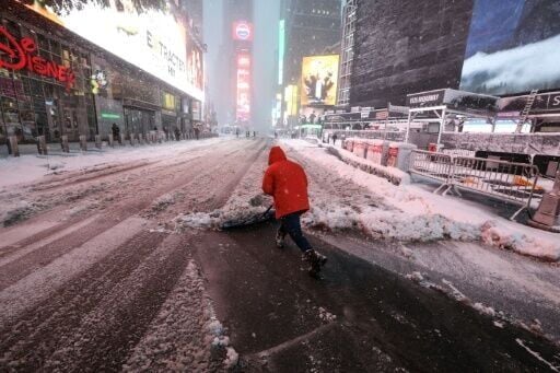 A worker clears a snow-covered street in Times Square early Monday in New York