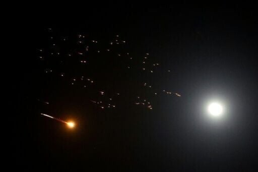 Rocket trails are seen next to the moon in the sky above Netanya