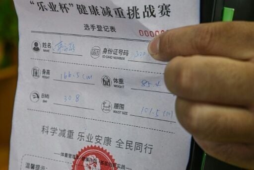 Staff members measure slimmers' waists, log their data on a form and use an encouraging stamp to mark it and cheer them on