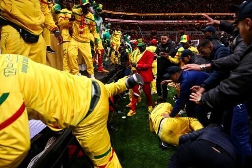 Angry Senegal fans are stopped from entering the pitch by security personnel