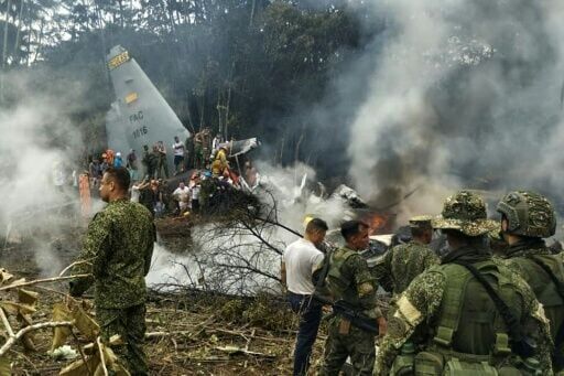 Military personnel clambered over the wreckage of the Hercules transport plane, enveloped in smoke