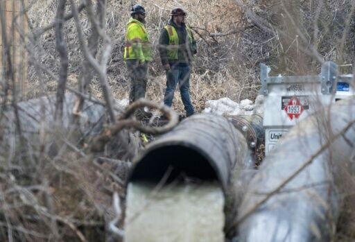 Emergency workers look on as raw sewage flows out of a drainage pipe into the C&O Canal near Cabin John, Maryland, after more than 200 million gallons of wastewater spilled into the Potomac River