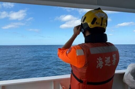 This handout photo taken and released on December 29, 2025, by the Taiwan Coast Guard shows a coast guard administration crew member observing Chinese coast guard ship No. 1303 from the CGA's "Yilan" patrol vessel 23 nautical miles northwest of Pengjia ...