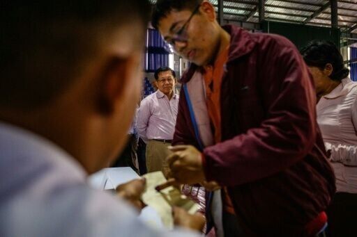 Military chief Min Aung Hlaing (back C) watches a voter ink their finger as he visits a polling station during the final phase of Myanmar's general election in January