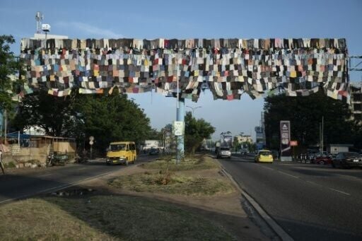 Cars drive under a billboard covered with clothes as part of the 'Baleboard' project in Accra