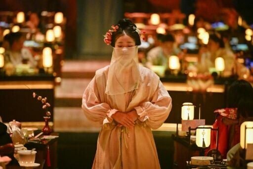 A waitress in traditional Chinese clothes waiting to serve customers at a theatrical restaurant in Beijing