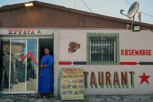 A migrant poses in the door of her shop and restaurant in the "Un Nuevo Amanecer” (A New Dawn) neighbourhood near Chile's capital Santiago