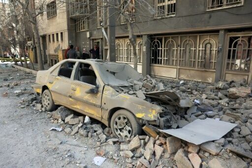 Residents stand amid the debris of a building following air strikes in central Tehran