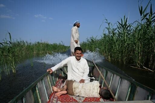 A boy rests as fishermen ride in their boat through the transboundary marshes shared by Iraq and Iran
