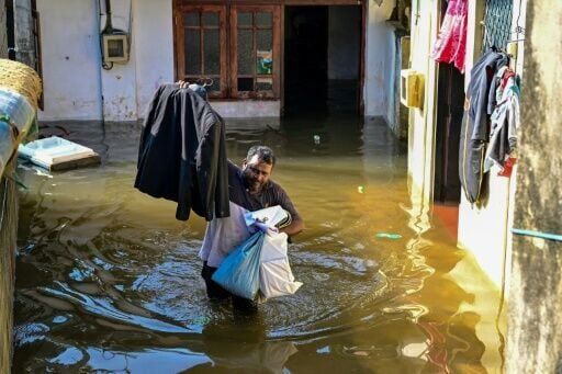 A man wades through floodwaters outside his house in Wellampitiya on the outskirts of Colombo