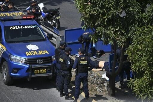 A Public Ministry prosecutor collects evidence near the body of a police officer killed by alleged gang members in Guatemala City