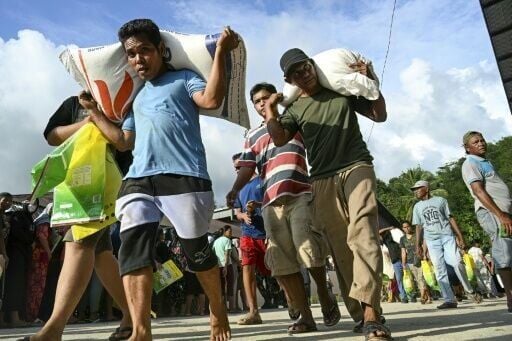 Flood survivors receive sacks of rice the government's warehouse at Sarudik, in North Sumatra