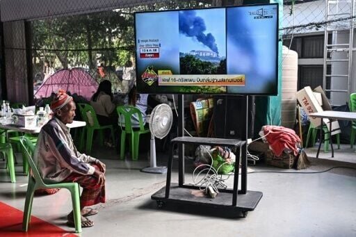 A displaced resident watches the news at an evacuation center in the Thai border province of Surin on December 11, 2025