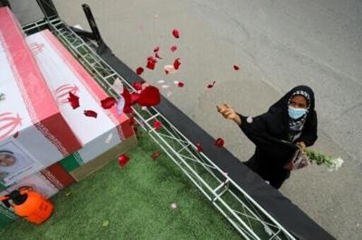 In this handout picture from Iranian state media, a mourner tosses flower petals on the coffins of children who were killed in a reported strike on a primary school in Iran’s Hormozgan province during a funeral