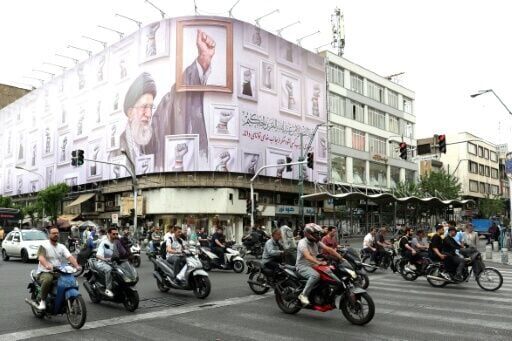Iranians drive past a billboard in Tehran with the image of late supreme leader Ayatollah Ali Khamenei, killed in the US-Israeli strikes that started the war in February