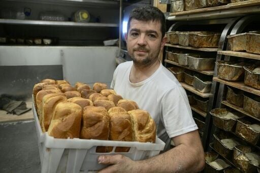 Loic Nervi kneads the dough vigorously before sliding dozens of tins into the oven -- loaves that will later be handed out to Ukrainians.