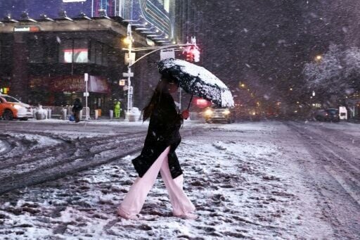 A woman crosses Manhattan's 8th Avenue during snowfall in New York City