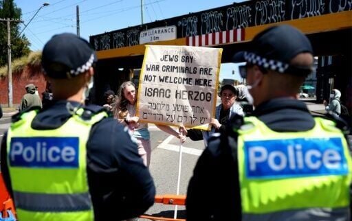 Police officers cordon off a venue as protesters gather during the visit of Israel's President Isaac Herzog in Melbourne on February 12, 2026