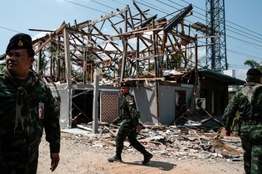 Thai soldiers walk outside the damaged remains of a house during a military organised tour near Klong Paeng on February 5, 2026, in an area now controlled by the Thai forces following the border conflict with Cambodia