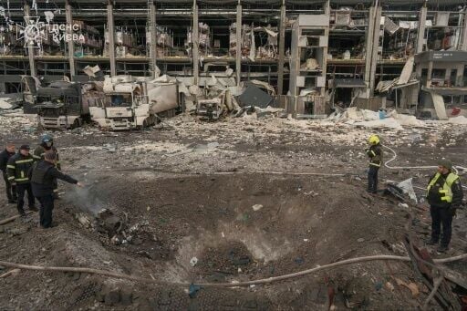Ukrainian law enforcement officers inspect a crater at the site of an air attack in Kyiv
