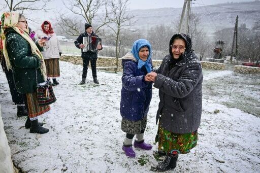Maria Ardeleanu (second left), 86, dances with a friend outside a 'hobbit house'