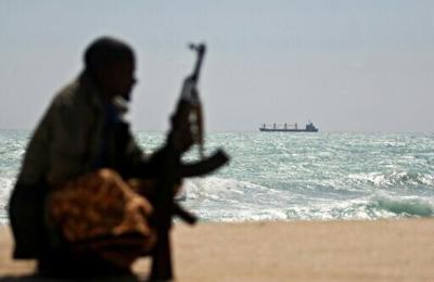 An armed Somali watches a Greek cargo ship anchored off NE Somalia in 2010