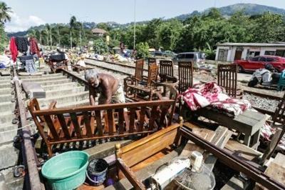 A Sri Lankan flood victim sorts out his belongings by railway tracks in Kandy. The authorities have issued fresh landslide warnings as monsoon storms make hillsides unstable