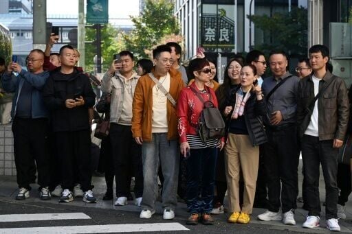 A Chinese tour group waits to cross a road at the Ginza shopping district of Tokyo on November 16. Beijing has advised its citizens to avoid travelling to Japan, following a diplomatic feud sparked by remarks from Tokyo's new premier about a hypothetica...