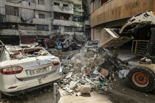 Workers clear debris from a street after an Israeli strike in central Beirut'