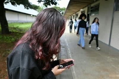 A young student uses her mobile phone at a public school in Planaltina, Brasilia