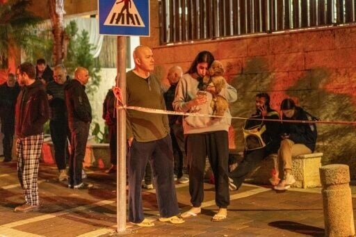 People gather outside a building hit by a projectile in a city in outskirts of Tel-Aviv