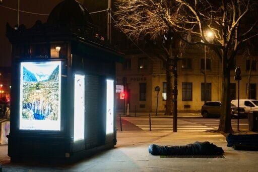 A homeless person tries to keep warm on top of an airing vent in Paris