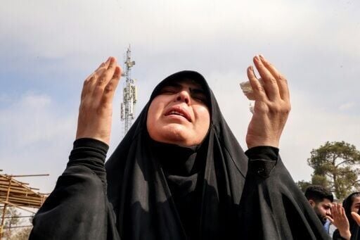 A mourner prays during the burial of a person killed in recent US-Israeli airstrikes at a grave in a cemetery in Tehran