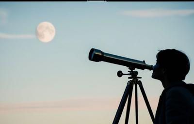man looking at sky through telescope
