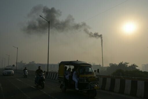 Smoke billowing from a factory chimney as commuters make their way through smoggy conditions in Amritsar, India