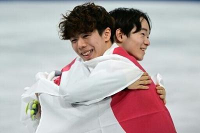 Japan's Yuma Kagiyama and Shun Sato hug each other after taking silver and bronze respectively in the Olympic men's singles free skating event in Milan