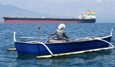 A fisherman travels past the Sara Sky, which last week arrived in the Philippines bearing crude oil from Russia