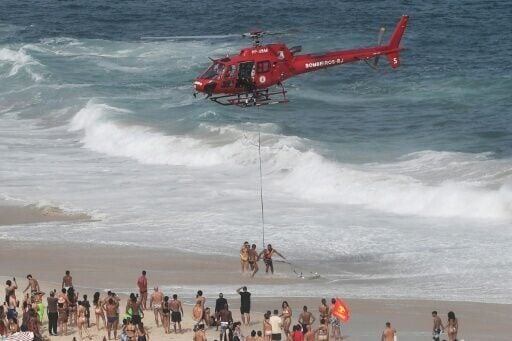 A helicopter rescues a swimmer at Copacabana beach, where authorities expect the world's biggest New Year's Eve party
