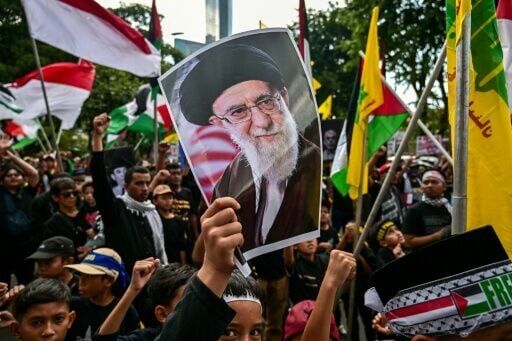 A boy holds a poster of Iran's slain supreme leader Ayatollah Ali Khamenei during an al-Quds (Jerusalem) Day rally in Surabaya, Indonesia on March 13, 2026
