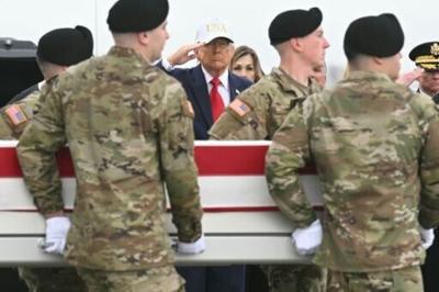 President Donald Trump salutes as members of an Army team carry a case containing the remains of one of six US soldiers killed in an Iranian strike on a US command center in Kuwait